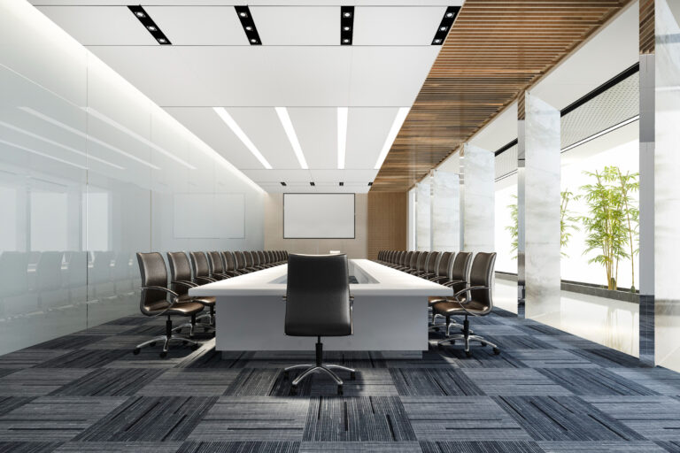 Large modern conference room with a long white table, black rolling chairs, and a projector screen at the front of the room.