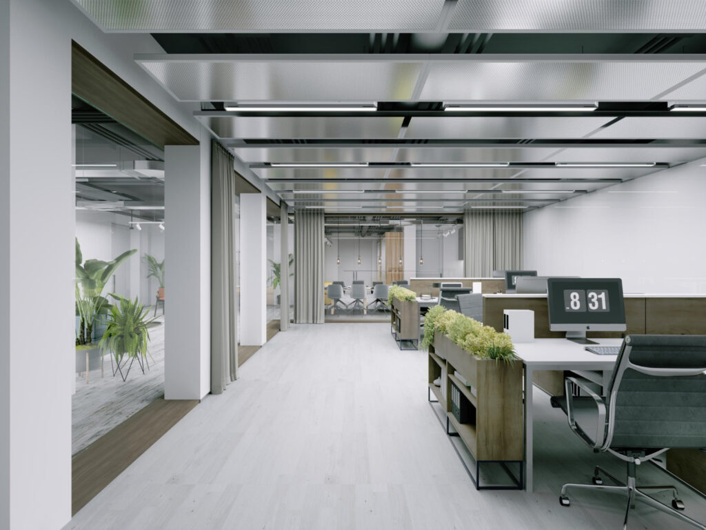 Open-plan office with white desks, grey chairs, and potted plants; glass-walled meeting room visible in the back.